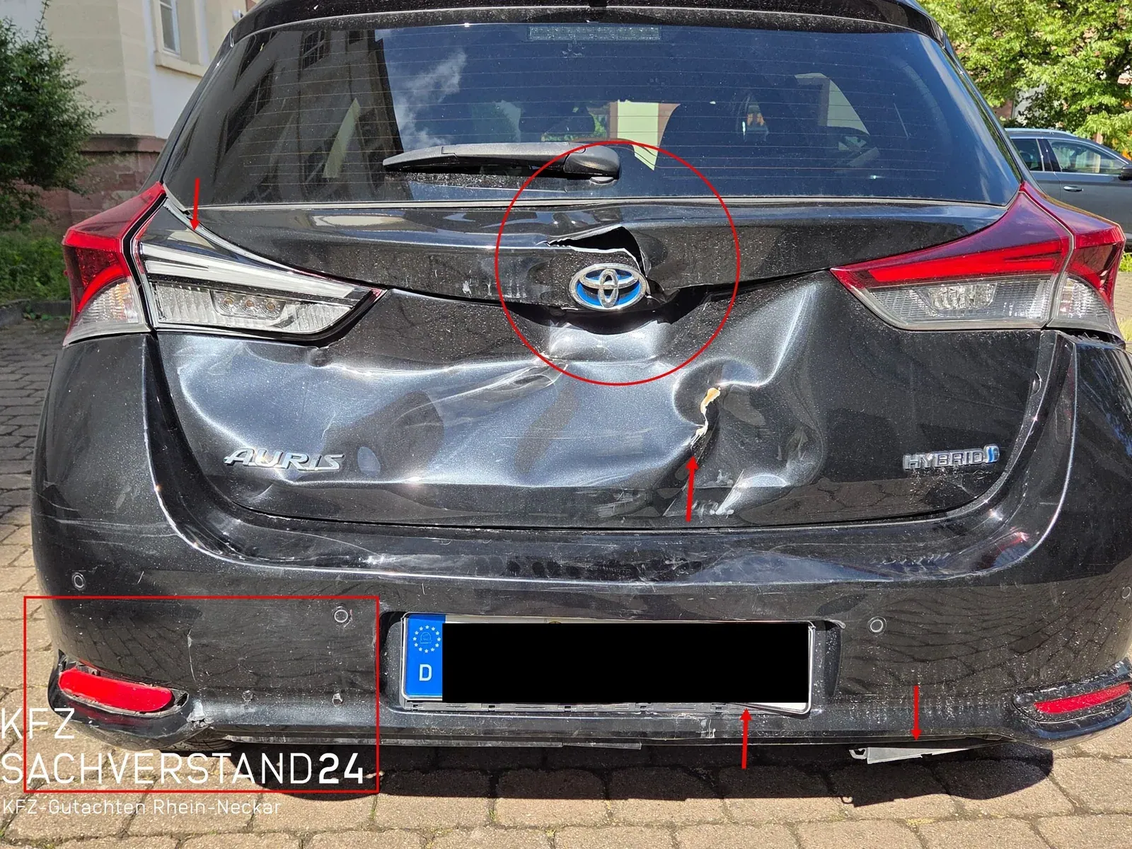 Schwarzer Toyota Auris Hybrid mit Heckschaden: eingedrückte Heckklappe und Stoßfänger, Schadenstellen rot markiert