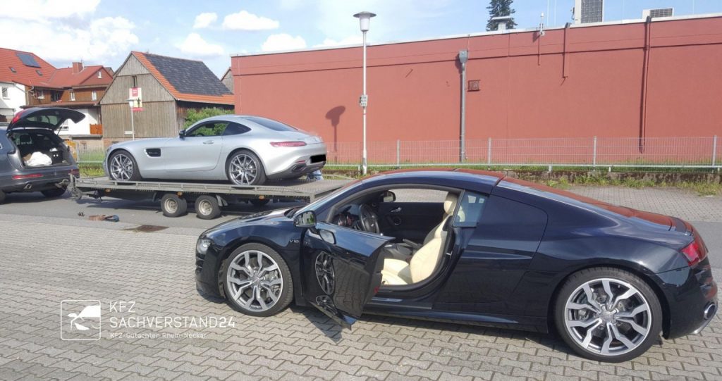 Schwarzer Audi R8 mit offenen Türen neben einem silbernen Porsche auf einem Abschleppwagen.