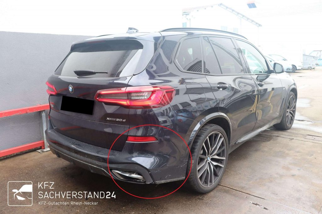 BMW X5 xDrive30d mit sichtbaren Kratzern an der hinteren Stoßstange auf einem Parkplatz.