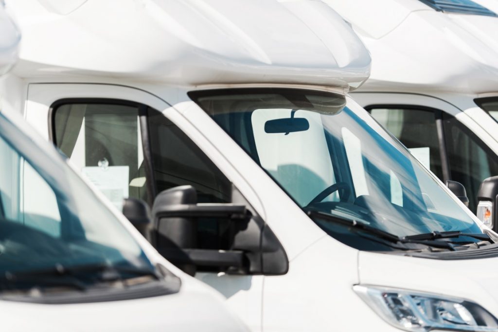 Weiße Wohnmobile in einer Reihe geparkt, Nahaufnahme der Frontansicht und Windschutzscheiben.
