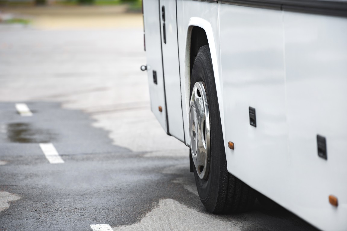 Nahaufnahme eines weißen Busreifens auf nasser, asphaltierter Straße. Verkehrssicherheit nach Regen.